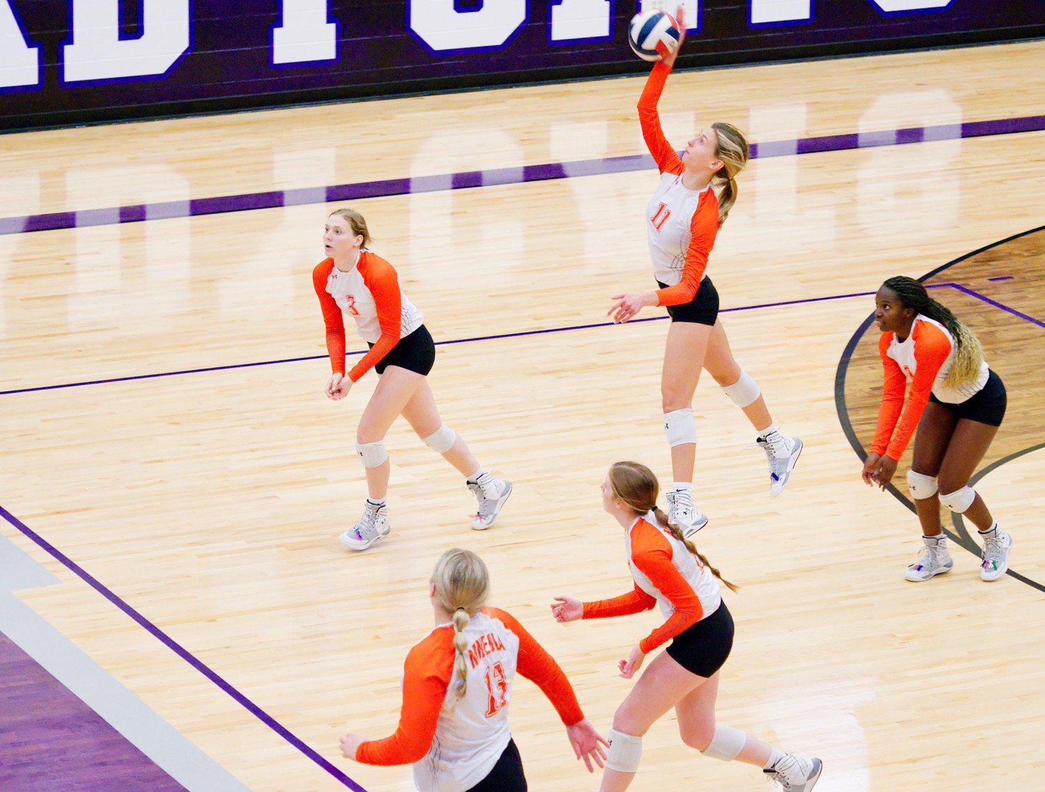 Clockwise from top left, Lady Jacket players Mylee Fischer, Olivia Hughes, Shylah Kratzmeyer, Macy Fischer and Jocelyn Whitehead spread across the floor as Hughes takes a swipe at the ball. [view more volleyball shots]